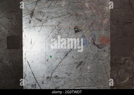 A silver-colored square with triangles, stripes and a spot of light appears on a brown-gray concrete wall in an expressionistic look. Stock Photo