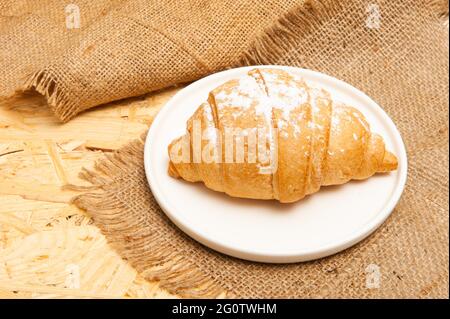 Croissant on a saucer and on a canvas napkin. Top view Stock Photo