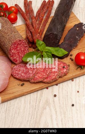 Different types of sausages with tomatoes and herbs on a wooden board. Top view Stock Photo