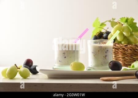 Organic grape drink on white plate with bunches of white and red grapes in basket on wooden table isolated background. Front view. Stock Photo