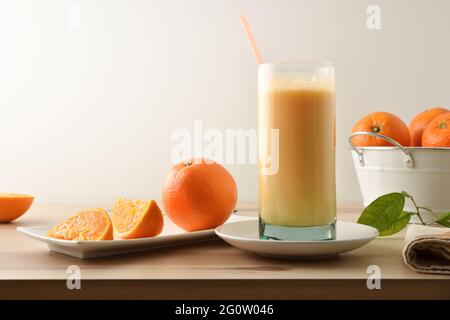Natural orange beverage with milk and fruit bowl full of oranges on wooden table isolated background. Front view. Stock Photo