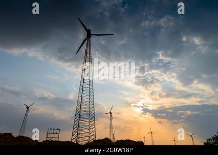 Silhouette of wind mills in twilight with a setting sun and cloudy sky in background, Rajasthan, India Stock Photo