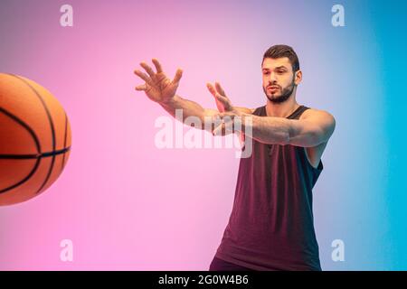Focused sportsman throw basketball ball in studio Stock Photo