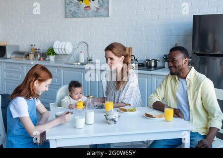 smiling multiethnic family having breakfast in kitchen Stock Photo
