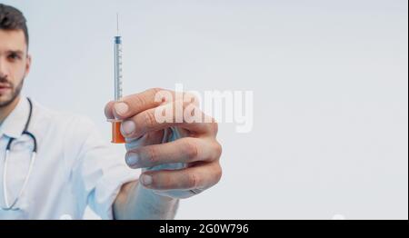 European male doctor watching syringe in hand Stock Photo
