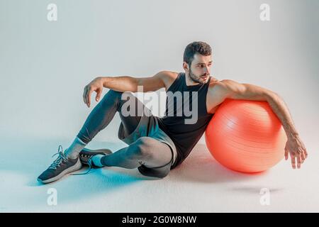 Sportsman sitting on floor with fitness ball Stock Photo