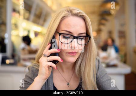 Adult blond woman speaking on phone Stock Photo