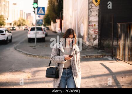 Non-binary woman using smart phone while walking in city Stock Photo