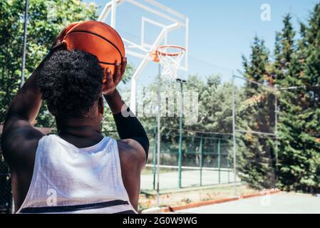 Rear view of an African-American Black Boy ready to shoot the ball into the basket. Stock Photo