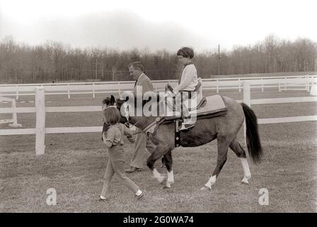 KN-27639  31 March 1963  Weekend at Camp David. Sally Fay riding horse 'Macaroni' lead by Paul 'Red' Fay and Caroline Kennedy. 'Macaroni' wears a Moroccan saddle given to the Kennedy's by King Hassan II of Morocco. Camp David, Maryland.  Please credit 'Robert Knudsen. White House Photographs. John F. Kennedy Presidential Library and Museum, Boston' Stock Photo