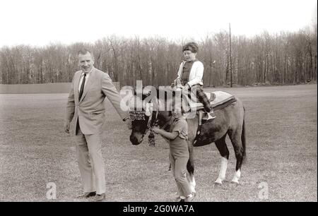 KN-27636  31 March 1963  Weekend at Camp David. Sally Fay riding horse 'Macaroni' lead by Paul 'Red' Fay and Caroline Kennedy. 'Macaroni' wears a Moroccan saddle given to the Kennedy's by King Hassan II of Morocco. Camp David, Maryland.  Please credit 'Robert Knudsen. White House Photographs. John F. Kennedy Presidential Library and Museum, Boston' Stock Photo