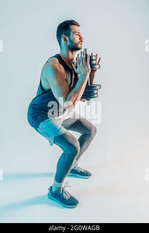 Concentrated young man sit ups with dumbbells Stock Photo