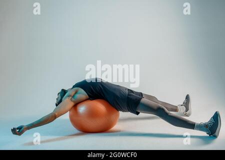 Sportsman lying on fitness ball after training Stock Photo