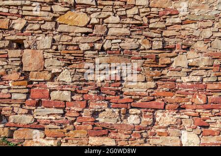 Old vintage stone wall made of untreated red stone. Stock Photo