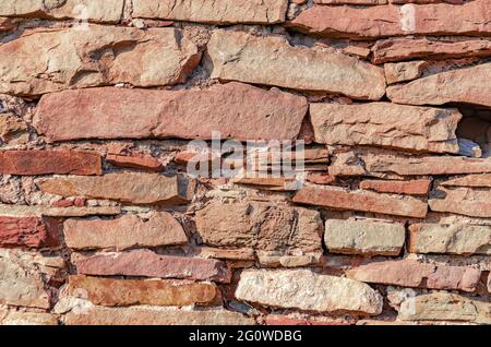 Old vintage stone wall made of untreated red stone. Stock Photo