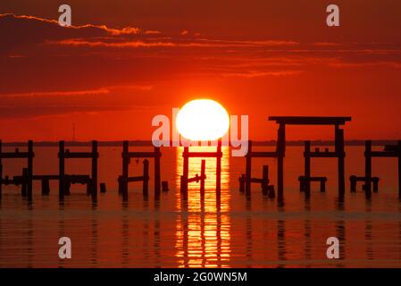 The sun sets beyond the remains of a pier in Fairhope, Alabama. Stock Photo