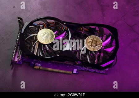 On the fans of a powerful video card, the coins of the Bitcoin cryptocurrency with a red backlight are displayed.The concept of mining and mining of c Stock Photo