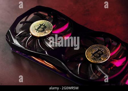 On the fans of a powerful video card, the coins of the Bitcoin cryptocurrency with a red backlight are displayed.The concept of mining and mining of c Stock Photo