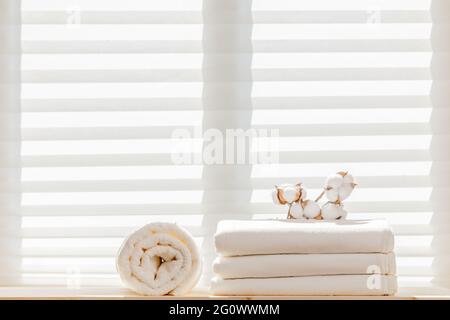 White linens bed linen sheets with a cotton branch and a terry towel against the background of the window. Natural composition. Stock Photo