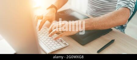 Writer typing modern computer keyboard writing novel sitting at the white wood table. Distance or freelance work on worldwide quarantine time concept Stock Photo