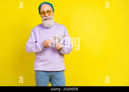 Photo of lucky funny age gentleman wear violet sweater headwear eyeglasses counting dollars empty space isolated yellow color background Stock Photo