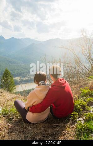 Young traveler couple resting and taking selfie in the mountains. Man and woman hiking with backpacks on a beautiful rocky trail. Family local travel Stock Photo