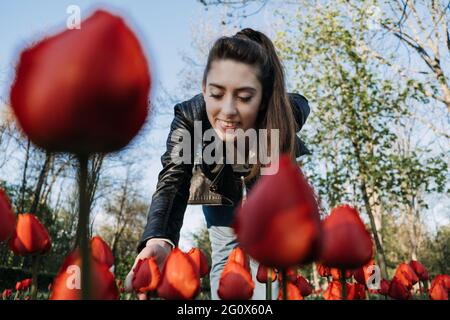 Enjoy every moment, Enjoying life, Positive emotions, Ways to Be Happier. Happy Young woman jumping and enjoying life at green park with flowers. Stock Photo