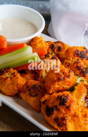 Vegetarian cauliflower buffalo wings served with blue cheese dipping sauce and sliced carrots and celery Stock Photo