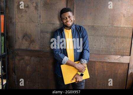 Portrait of an attractive smiling confident casual young man looking at camera, college student or freelancer, standing over background, carrying Stock Photo