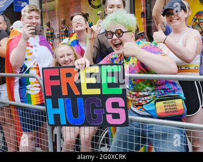 Revellers hold up a 'Free hugs' placard as they watch the Jubilee Pride in London parade Stock Photo