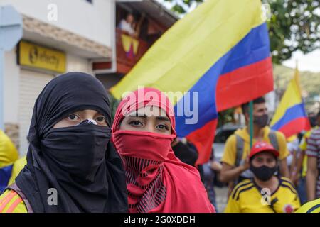 Yumbo, Colombia. 02nd June, 2021. A couple covering their faces poses for a photo with the colombian national flag behind as demonstrations against the government of president Ivan Duque rise admist police brutality and unrest that resulted in at least 70 dead during the first month of demonstrations. In Yumbo, Valle del Cauca, Colombia on June 2, 2021. Credit: Long Visual Press/Alamy Live News Stock Photo