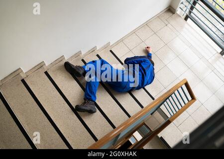 Worker Man Lying On Staircase After Slip And Fall Accident Stock Photo