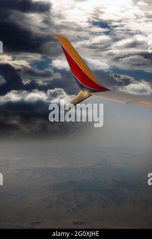 View from the window of a wing-tip of a Southwest Airlines Boeing 737-800 in flight over the Mojave Desert in California at sundown Stock Photo