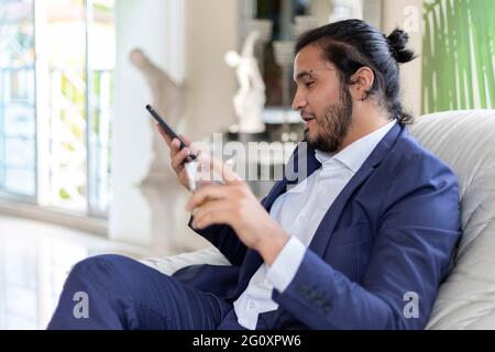 selective focus of businessman using smart phone and holding glass. Home Office Stock Photo
