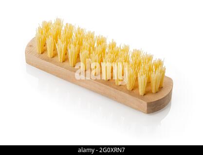 Close-up of new wooden cleaning brush with coarse stiff yellow bristles isolated on white background. Vintage design element for housework and cleanin Stock Photo