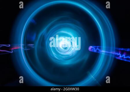 Round plasma laser flashes and fast rotation storm movement as abstract neon electric tunnel background. Stock Photo