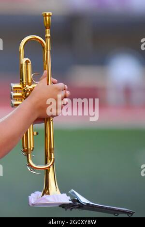 A marching band musician holds his trumpet before taking the field. The image features copy space to the right of the main subject. Stock Photo