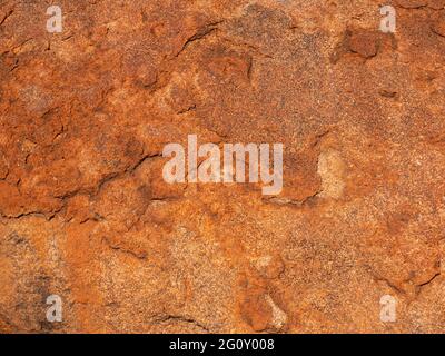 Red coloured textured granite rock face background with copy space Stock Photo