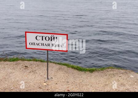 Stop danger zone. The sign on the edge of the cliff. The edge of the shore with a high cliff. Stock Photo