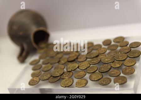 Clay pot with coins. Old Greek coins are scattered on the Plexiglass. Stock Photo