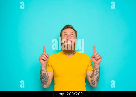 Man with yellow t-shirt and beard is surprised about something Stock Photo
