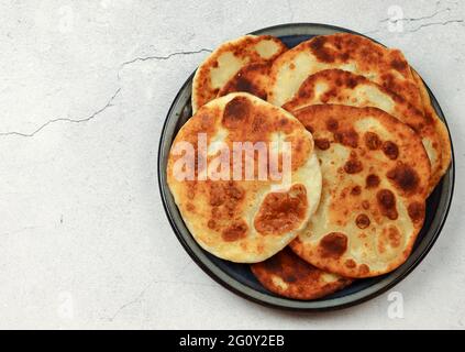 Homemade buttermilk cheese pita on a round plate on a light gray background. Top view, flat lay Stock Photo