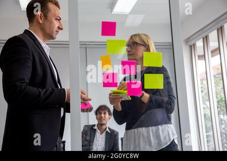 Businessman and Businesswoman tracking tasks on board. Using task control of agile development methodology in the office Stock Photo