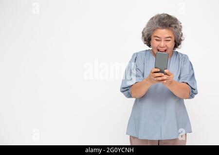 Asian senior woman using smartphone and receiving good news from the message on mobile chat application over white background Stock Photo