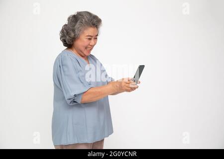 Asian senior woman using smartphone and receiving good news from the message on mobile chat application isolated over white background Stock Photo