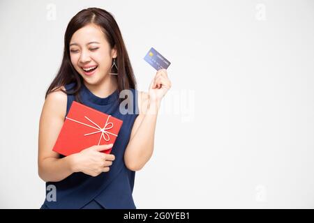 Happy Asian beautiful woman holding red gift box and credit card on hand isolated on white background Stock Photo