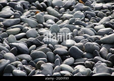 Round stones on a dry river bed outside in nature. Smooth pebbles with light gray tones in ambient light. Stock Photo