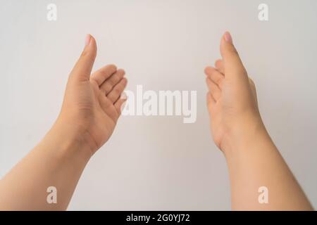two open empty female hands with palms up, holding something, isolated on white background. Selective focus. Stock Photo
