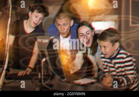 Happy family using computer in closed escape room stylized as bunker Stock Photo