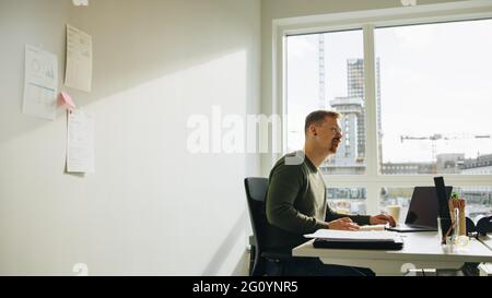 businessman working at desk in office. Manager looking away and thinking while at work. Stock Photo